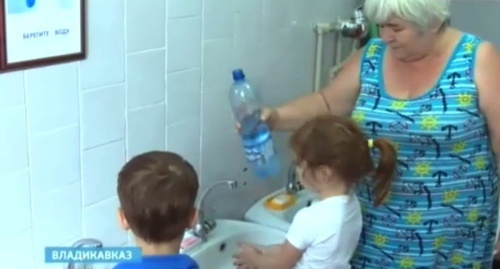 Сотрудница детсада во Владикавказе поливает детям руки кипяченой водой. Скриншот из сюжета телеканала "Россия-Алания", Alaniatv.ru Сотрудница детсада во Владикавказе поливает детям руки кипяченой водой. Скриншот из сюжета телеканала "Россия-Алания", Alaniatv.ru