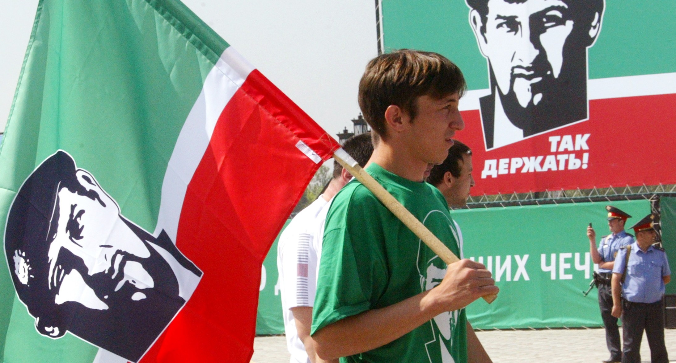 Молодой человек в Грозном с флагом с портретом Кадырова. REUTERS/Said Tsarnayev