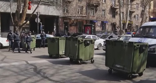 Сотрудники полиции возле мусорных баков, которыми перегородили дорогу во время акции протеста. Ереван, 16 марта 2021 г. Скриншот видео https://news.am/ https://news.am/rus/news/633964.html