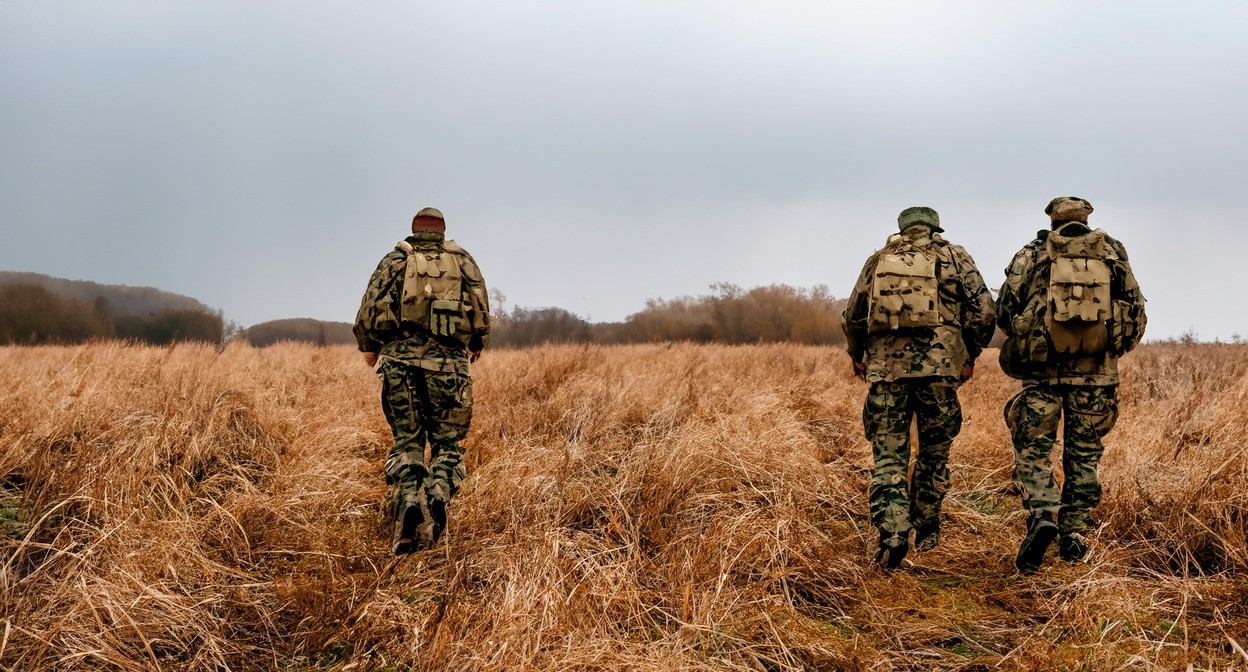 Военные идут по полю. Иллюстрация создана «Кавказским узлом» с помощью ИИ в программе Photoshop
