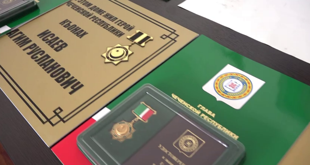 Мемориальная доска и награда убитому бойцу. Стоп-кадр видео префектуры Висаитовского района от 06.09.25, https://t.me/visaitovskayaprefertura/1617
